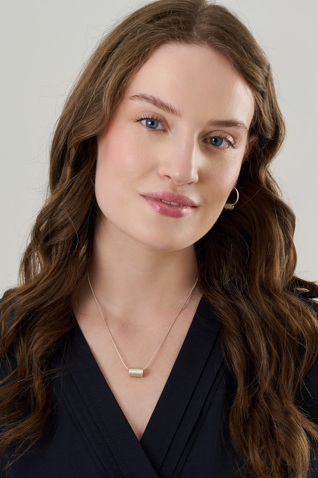 Sterling silver hoops with sterling silver coils and matching sterling silver coil necklace worn over a dark blue blouse