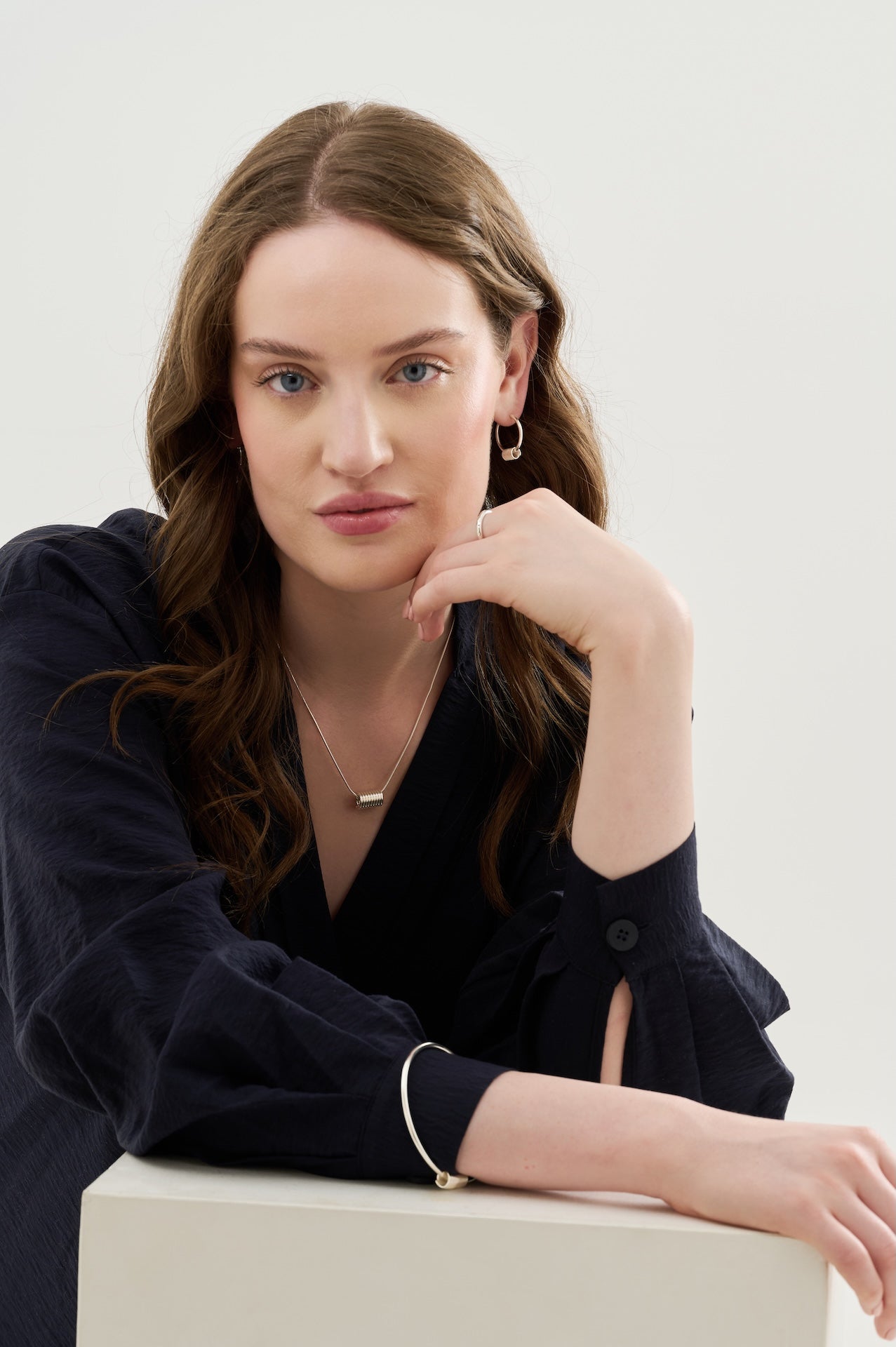 Sterling silver hoop earrings with coils matching coil pendant and coil bangle and sterling silver textured ring worn with dark blue blouse