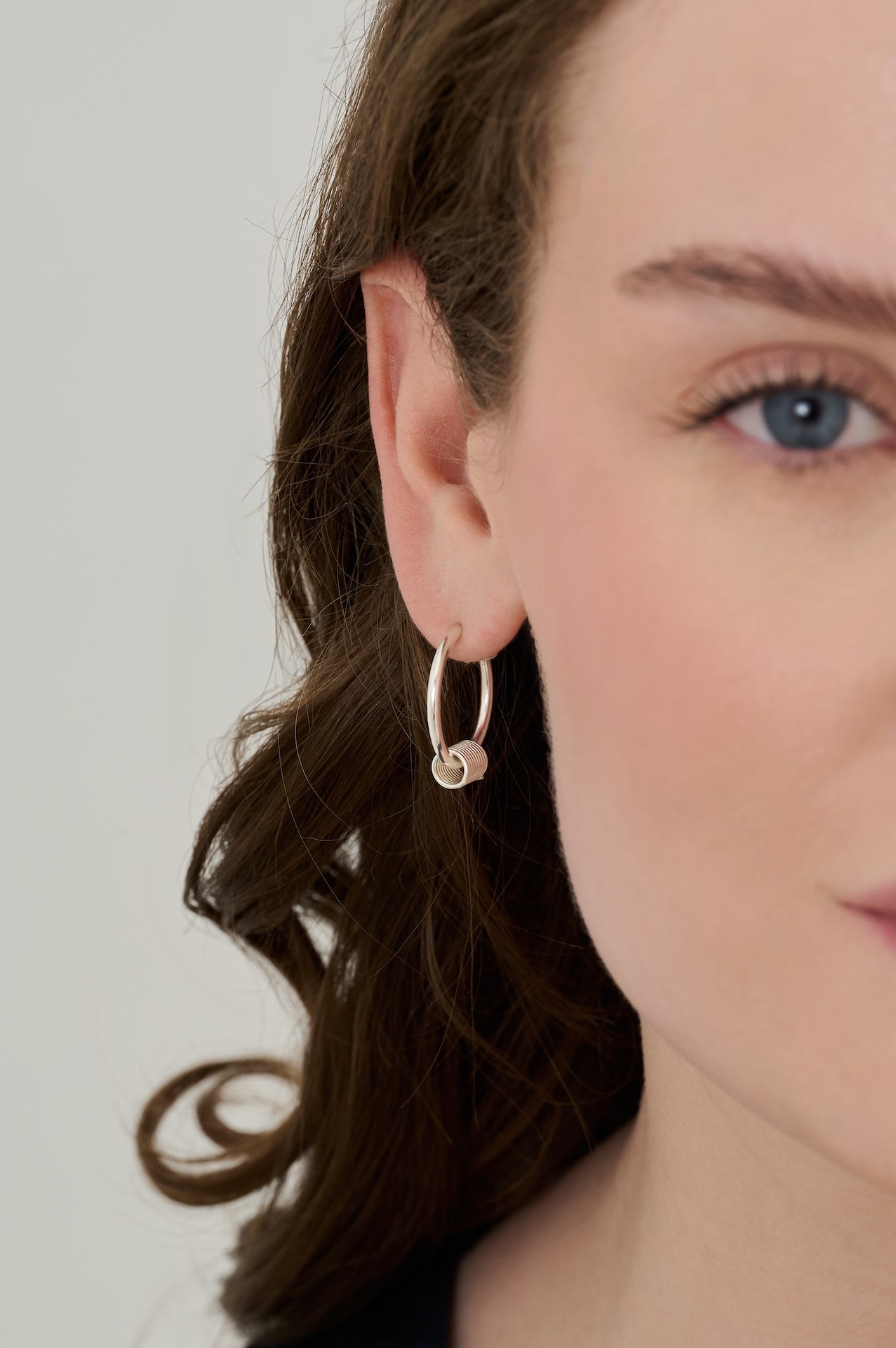 Sterling silver hoops with sterling silver coils worn front-facing with coil visible