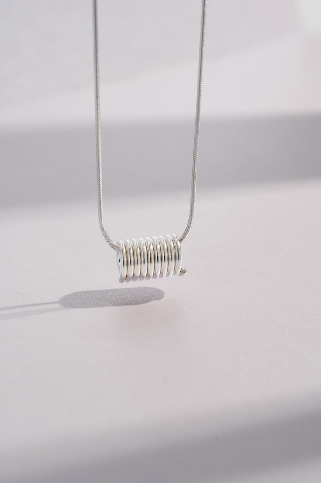 Sterling silver coil necklace on a 46-centimetre chain where the coil measures 13mm in length and 8mm in diameter and all inspired by Art Deco and minimalist architecture